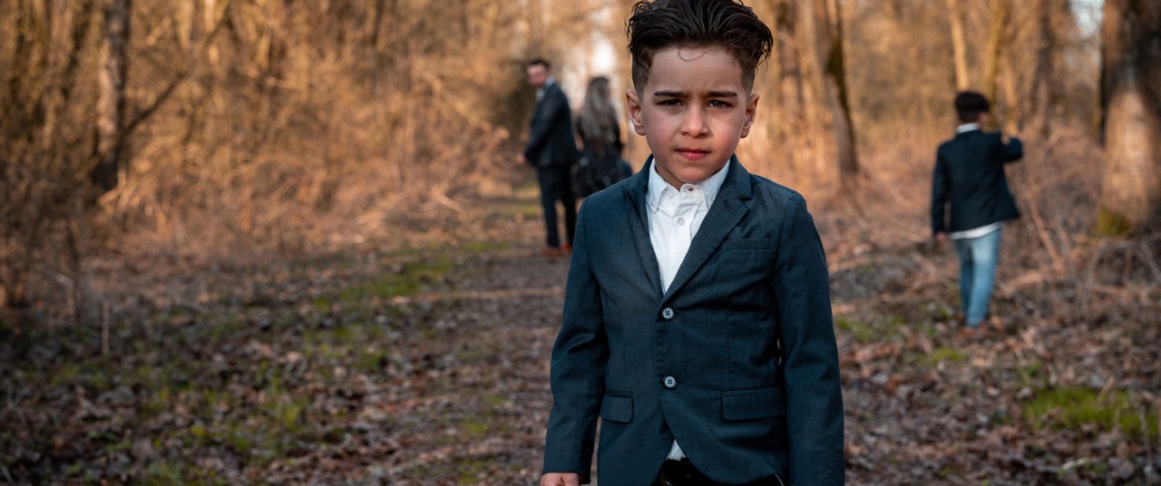 Lifestyle fotoshoot - Jongetje poseert, familie loopt achter hem in Dordrecht - Herman Fotografie