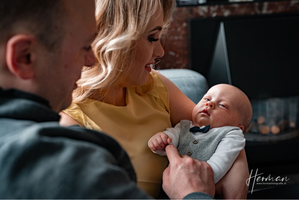 Lifestyle fotoshoot - Baby ligt in armen van moeder en vader thuis in Rotterdam - Herman Fotografie