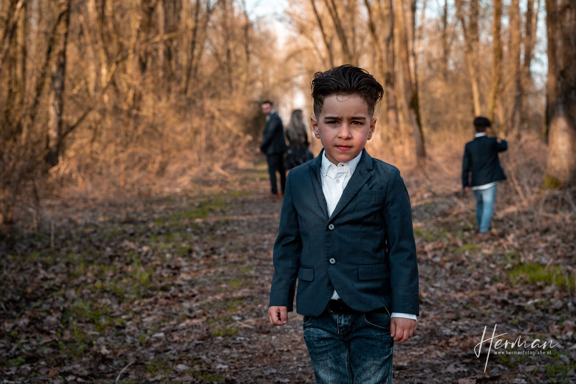 Lifestyle fotoshoot - Jongetje poseert, familie loopt achter hem in Dordrecht - Herman Fotografie