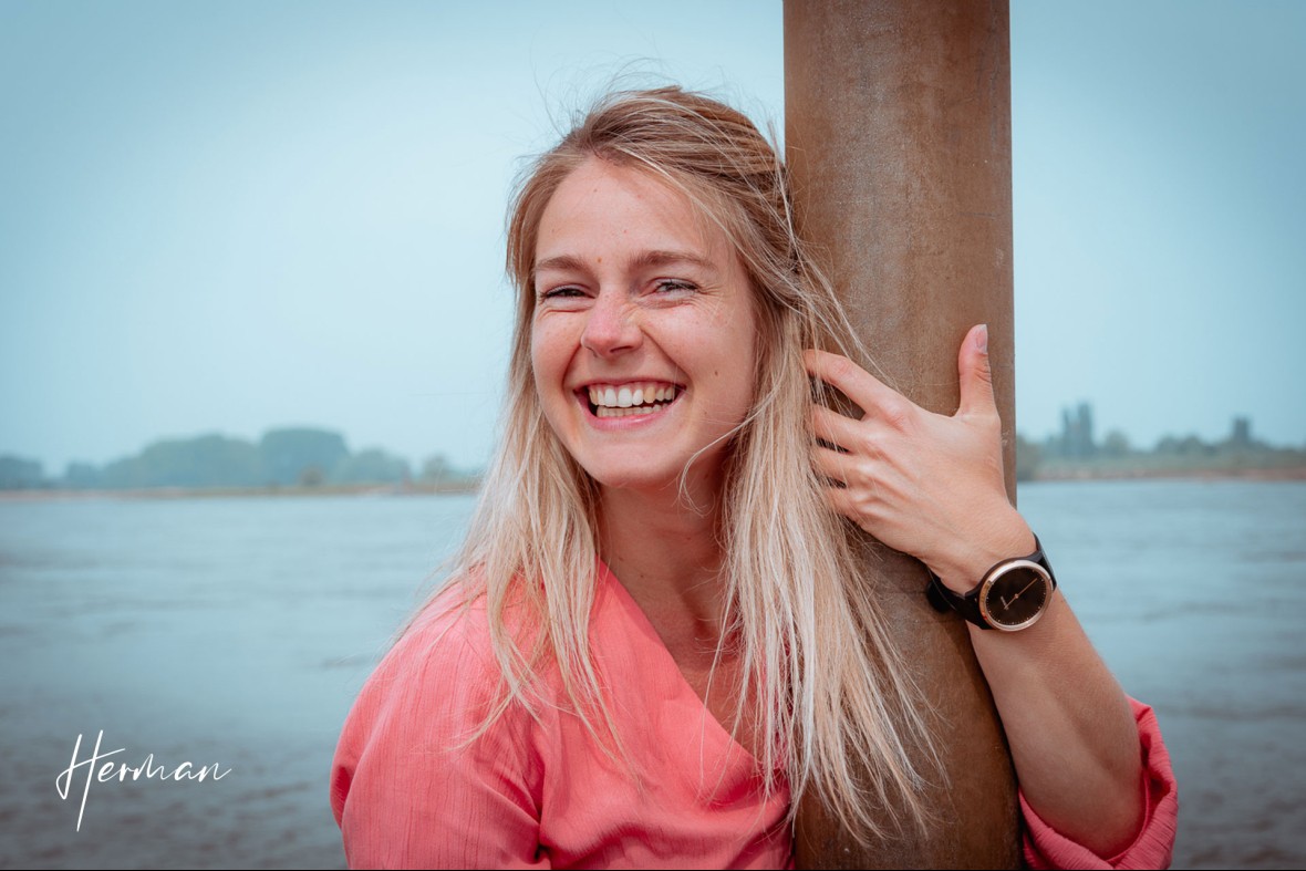 Claudia knuffelt een paal aan de Waal - Portret fotoshoot in Zaltbommel